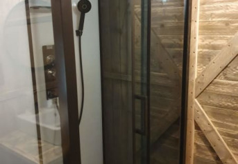 Moderne Duschkabine mit Glaswand und Holzwänden in einem Safarizelt bei Camping het Horstmannsbos, Niederlande.