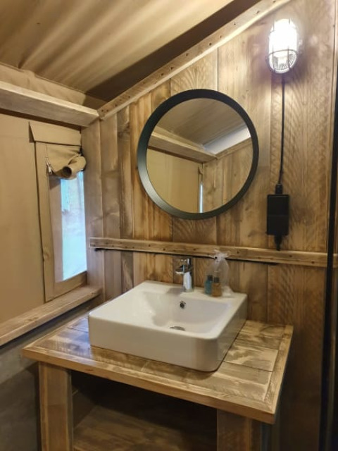 Bagno con pareti in legno rustico e lavandino quadrato in una tenda safari al Camping het Horstmannsbos.