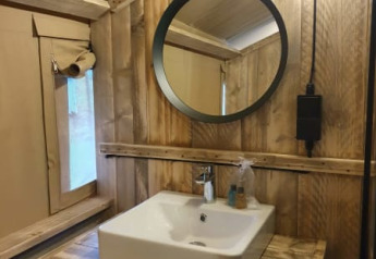 Bagno con pareti in legno rustico e lavandino quadrato in una tenda safari al Camping het Horstmannsbos.