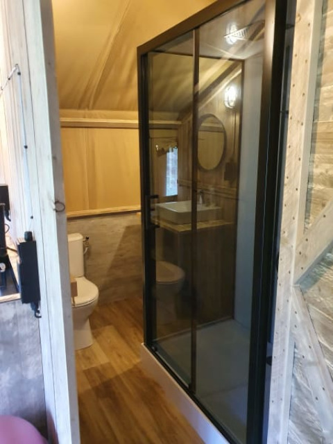 Bagno in tenda safari con doccia in vetro, WC e lavandino al Camping het Horstmannsbos, Paesi Bassi.