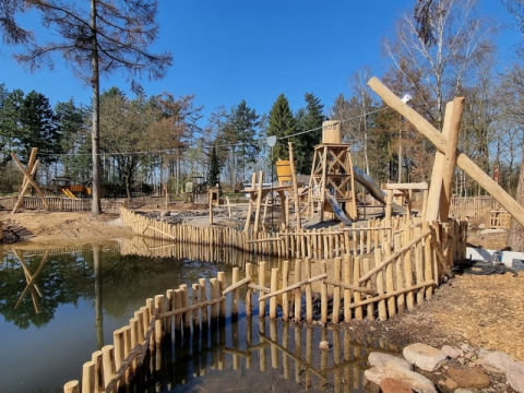 Parco giochi in legno con scivolo e acqua al Camping het Horstmannsbos, Paesi Bassi, in una giornata di sole.