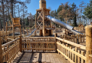 Parque infantil con tobogán y vallas de madera en Camping het Horstmannsbos en los Países Bajos.