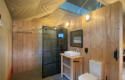 Baño moderno con paredes de madera y techo de lona en la tienda Luxe Safari en Camping het Horstmannsbos