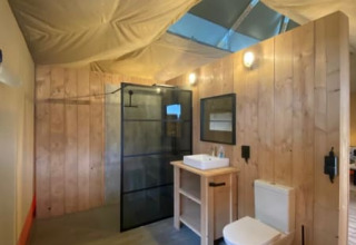 Baño moderno con paredes de madera y techo de lona en la tienda Luxe Safari en Camping het Horstmannsbos
