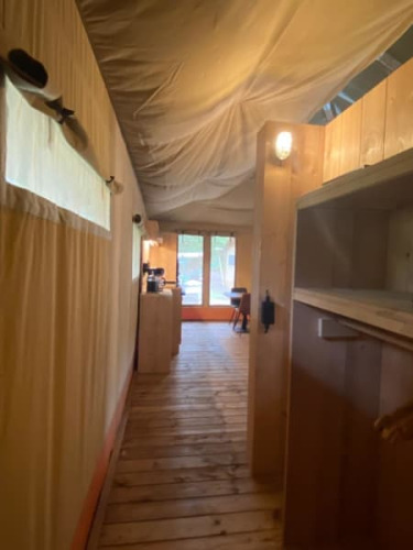 Vista interior de una tienda safari de lujo con suelo de madera y paredes de lona en Camping het Horstmannsbos.