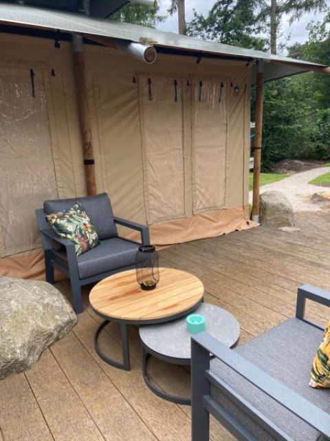 Patio esterno di una tenda safari di lusso con sedute moderne al Camping het Horstmannsbos, Paesi Bassi.