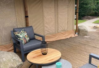 Terraza exterior de una tienda safari de lujo con asientos modernos en Camping het Horstmannsbos, Países Bajos.