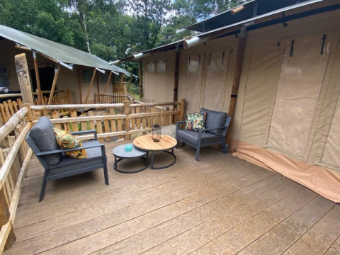 Terrasse extérieure avec sièges devant une tente safari Luxe au Camping het Horstmannsbos, Pays-Bas.