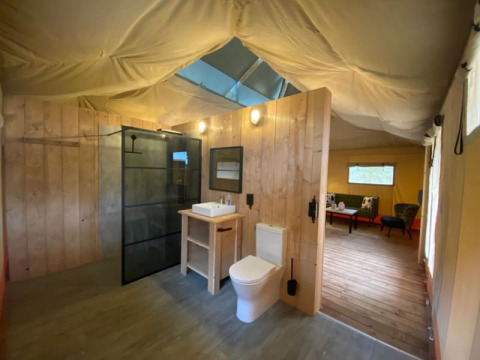 Vista interior de una tienda safari de lujo con baño moderno en Camping het Horstmannsbos, Países Bajos.