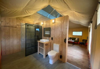 Interior view of a Luxe Safari tent with private modern bathroom at Camping het Horstmannsbos, Netherlands.