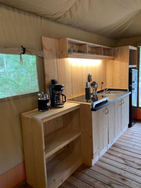 Wooden kitchen area with coffee makers in a luxury safari tent at Camping het Horstmannsbos, Netherlands.