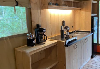 Cucina in legno con macchine da caffè in tenda safari di lusso al Camping het Horstmannsbos, Paesi Bassi.