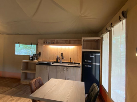 Intérieur d'une tente safari de luxe avec kitchenette, table et fenêtres au Camping het Horstmannsbos, Pays-Bas.