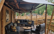 Zona de estar al aire libre en una tienda safari con muebles modernos en Camping het Horstmannsbos, Países Bajos.
