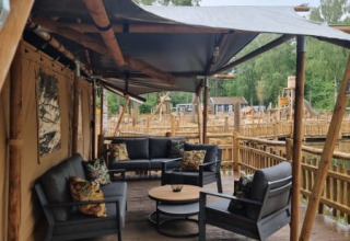 Outdoor seating area in a safari tent suite with modern furniture at Camping het Horstmannsbos, Netherlands.