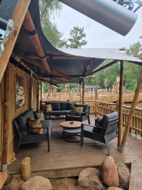 Zona de estar al aire libre en una tienda safari con muebles modernos en Camping het Horstmannsbos, Países Bajos.