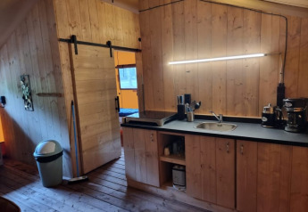 Vista interior de tienda safari en Camping het Horstmannsbos, Países Bajos, con paredes de madera y cocina.
