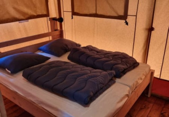 Dormitorio acogedor con cama doble en la tienda Safari tent + sanitary- Karper de Camping het Horstmannsbos.