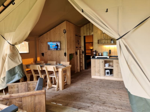Innenaufnahme eines komfortablen Safarizelts mit Holzmöbeln und Küche bei Camping het Horstmannsbos, Niederlande.