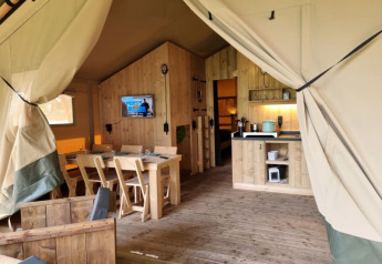Vista interior de una tienda safari elegante con muebles de madera en Camping het Horstmannsbos, Países Bajos.