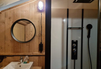 Modern safari tent bathroom at Camping het Horstmannsbos with wooden walls, sink, mirror, and shower.