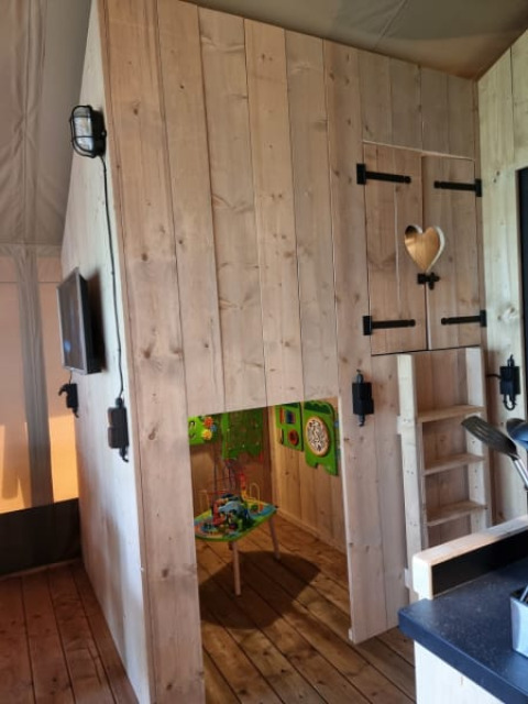 Vista interna dell'angolo giochi e angolo cottura nella Safari tent + sanitary al Camping het Horstmannsbos, Paesi Bassi.