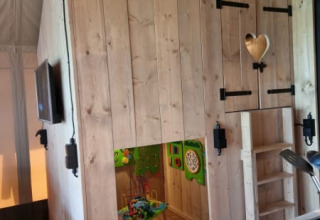 Indoor view of play nook and kitchenette inside Safari tent + sanitary at Camping het Horstmannsbos, Netherlands.