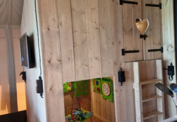 Indoor view of play nook and kitchenette inside Safari tent + sanitary at Camping het Horstmannsbos, Netherlands.