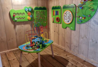 Wooden playroom with educational activity table and wall games in a safari tent at Camping het Horstmannsbos.