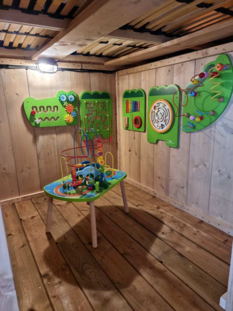 Houten speelruimte met educatieve speeltafel en wandspellen in een safaritent op Camping het Horstmannsbos.