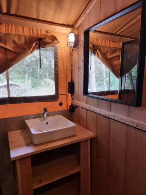 Interior of a safari tent at Camping het Horstmannsbos, Netherlands, featuring a sink, mirror and wood decor.