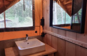 Interno di una tenda safari al Camping het Horstmannsbos, Paesi Bassi, con lavandino, specchio e arredo in legno.