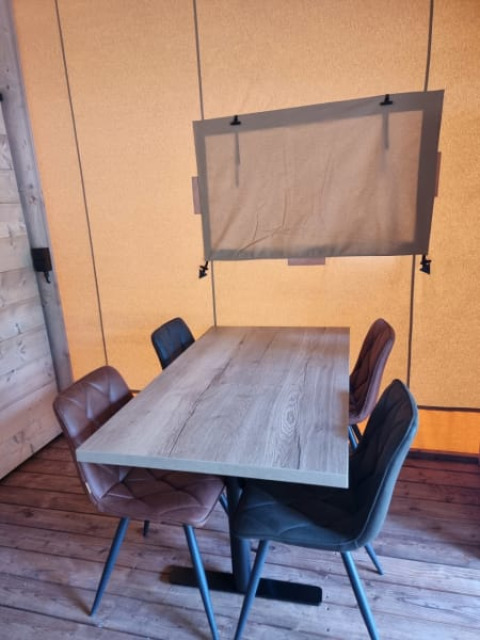 Wooden table with four chairs and a window in a canvas wall inside Safari tent + sanitary - Zeelt, Netherlands.