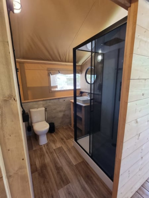 Safari tent bathroom at Camping het Horstmannsbos, Netherlands, featuring shower, toilet, and sink.