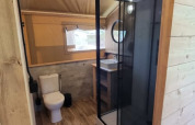 Salle de bain de tente safari au Camping het Horstmannsbos, Pays-Bas, avec douche, WC et lavabo.