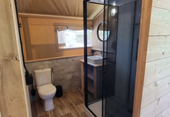 Salle de bain de tente safari au Camping het Horstmannsbos, Pays-Bas, avec douche, WC et lavabo.