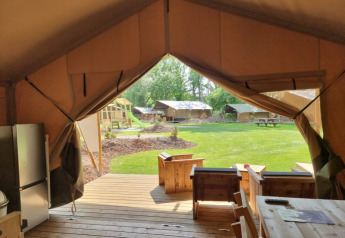 Vue depuis une terrasse de tente safari au Camping het Horstmannsbos, Pays-Bas, avec pelouse et aire de jeux.