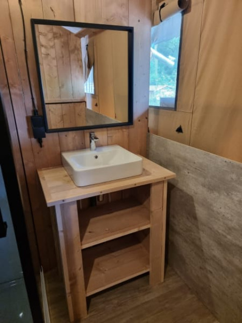 Badezimmer mit Holzwaschtisch, quadratischem Waschbecken und Spiegel in einem Safarizelt in den Niederlanden.