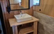 Bathroom with wooden sink stand, square basin and mirror inside a safari tent at Camping het Horstmannsbos.