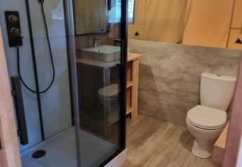 Modern safari tent bathroom with shower, toilet, and sink at Camping het Horstmannsbos in the Netherlands.