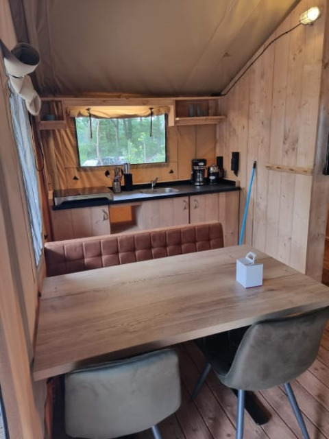 Interior view of Safari tent with kitchen and dining table at Camping het Horstmannsbos in the Netherlands.