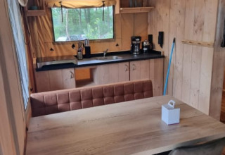 Interior view of Safari tent with kitchen and dining table at Camping het Horstmannsbos in the Netherlands.