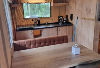 Vista interior de la tienda Safari con cocina y mesa de comedor en Camping het Horstmannsbos, Países Bajos.