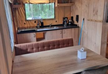 Interior view of Safari tent with kitchen and dining table at Camping het Horstmannsbos in the Netherlands.