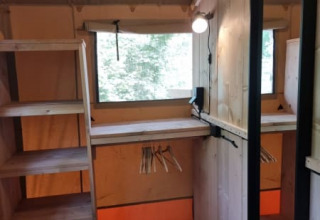 Interieur van Safari tent bij Camping het Horstmannsbos, Nederland, met houten planken, spiegel en raam.