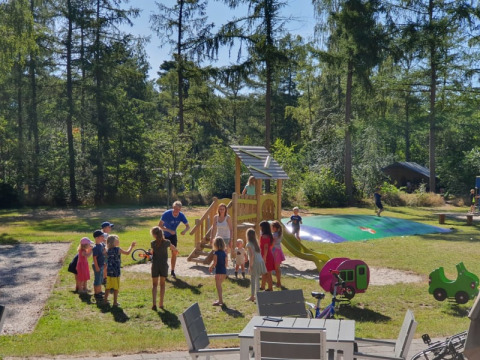 Kinder spielen und Erwachsene beaufsichtigen an einem Spielplatz mit Hüpfkissen im Wald in Holland.
