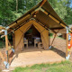 Safari telt kaldet Duolodge med træterrasse og to senge på en campingplads i en grøn skovomgivelse.