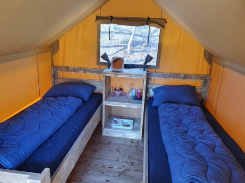 Innenraum eines Duolodge Safari-Zeltes mit zwei Einzelbetten und blauer Bettwäsche auf Camping het Horstmannsbos in den Niederlanden.