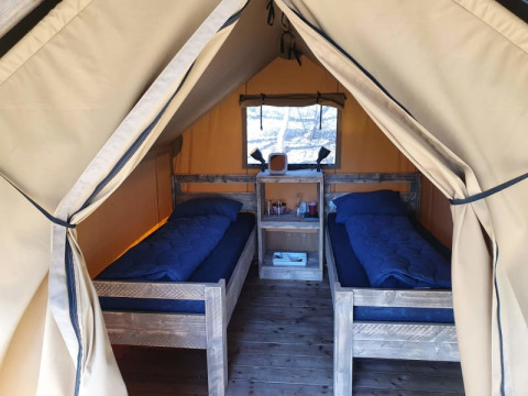 Indretning af en safari-telt med to enkeltsenge og træmøbler på Camping het Horstmannsbos i Holland.