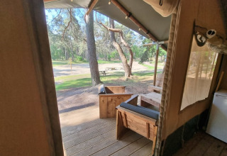 Vista desde una terraza de tienda safari con muebles de madera en Camping het Horstmannsbos, Países Bajos.